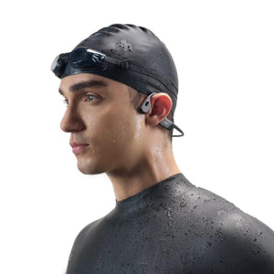 Swimmer wearing Shokz bone conduction headphones with a swim cap and goggles