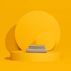 Folded grey bed sheets on a yellow circular platform
