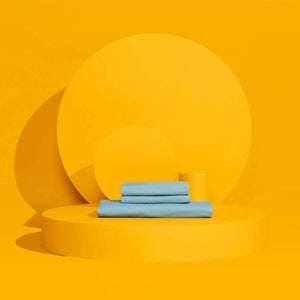 Stacked light blue bed sheets on a yellow circular platform
