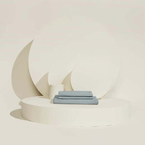 Folded blue bed sheets on a circular white platform