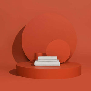 Stacked white bed sheets on a circular orange platform
