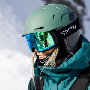 Person wearing a matte green Smith Optics helmet and blue mirrored goggles