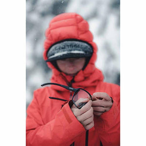 Person in red hooded jacket holding Smith Optics sunglasses