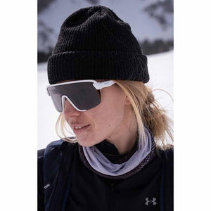 Person wearing a black beanie and white Smith Optics sunglasses in a snowy environment