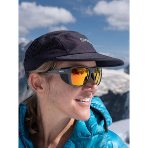 Person wearing Smith sunglasses and a black cap against a mountain background