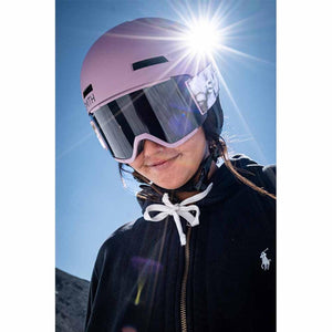 Person wearing a Smith Optics pink ski helmet and mirrored goggles against a bright blue sky