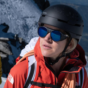 Person wearing a Smith helmet and blue sunglasses with a North Face jacket on a snowy mountain