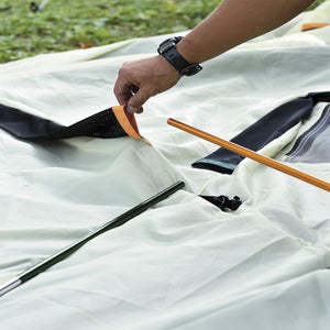 Person assembling a Snow Peak tent by inserting a pole into a color coded sleeve