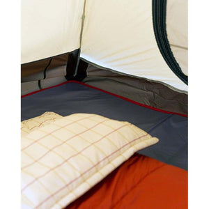 Interior of a Snow Peak tent with a plaid pillow and orange sleeping bag on the floor