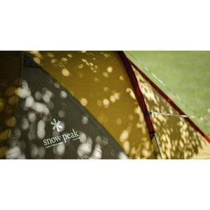 Snow Peak logo on a tent fabric with dappled light patterns