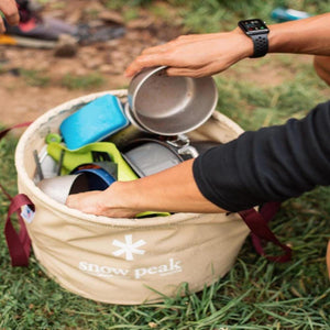 Person packing Snow Peak camp bucket with metal bowls and kitchenware