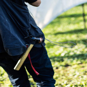 Person wearing black work apron with a hammer tucked into the waist loop
