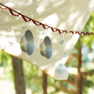 Two metal camping bowls and a small lantern hanging from a red daisy chain strap under a tent canopy