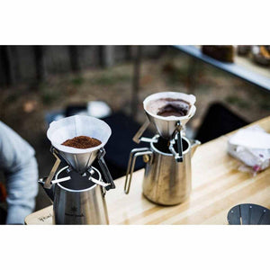 Two Snow Peak stainless steel coffee drippers on kettles with paper filters and coffee grounds