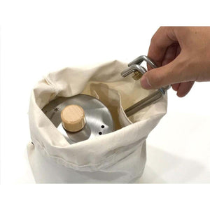 Hand placing a Snow Peak kettle into a canvas storage bag