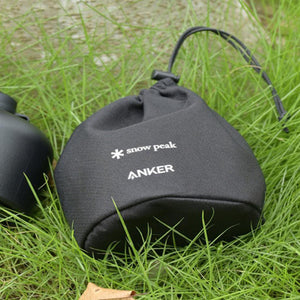 Black Snow Peak and Anker drawstring storage pouch on green grass