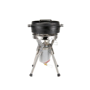 Cast iron dutch oven sitting on a portable camping stove with a fuel canister
