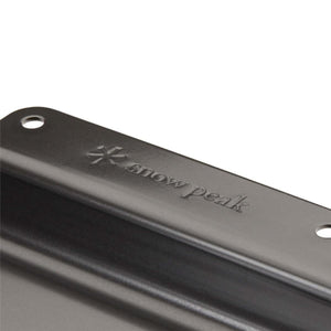 Close up of a black Snow Peak metal component with embossed logo and mounting holes