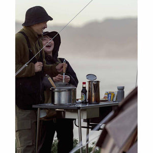 Two people cooking on a Snow Peak camping stove outdoors