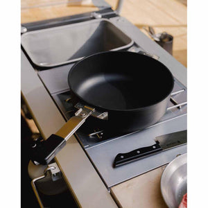 Snow Peak black frying pan with folding handle on a modular outdoor kitchen stove