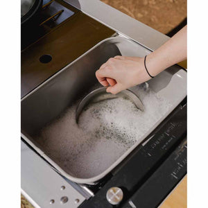 Hand washing a metal bowl in a Snow Peak camping sink