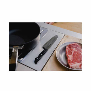 Snow Peak knife on a metal camp kitchen surface next to a raw steak in a metal bowl