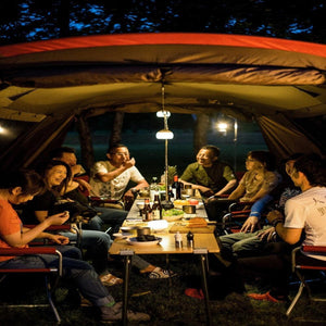 Group of people dining at a Snow Peak table inside a tent at night