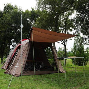 Snow Peak brown camping tent with extended canopy and metal table in a grassy field