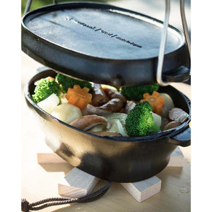 Snow Peak cast iron pot with lid lifted to reveal cooked vegetables and sausages