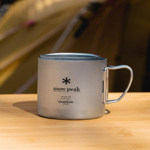 Snow Peak titanium 450 double wall mug with folding handle on wooden surface