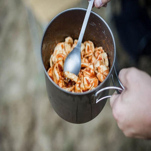 Snow Peak titanium pot filled with pasta and tomato sauce being stirred with a metal spoon