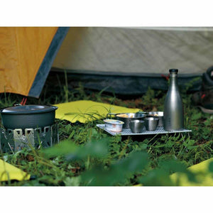 Camping stove with cookware and metal bottle on a folding table in front of a tent