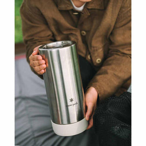 Person holding a stainless steel Snow Peak tumbler with a white silicone base
