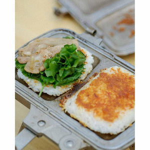 Snow Peak hot sandwich cooker containing a rice patty topped with lettuce and meat