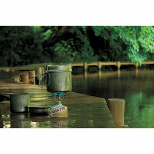 Snow Peak Giga Power stove with a metal pot on a wooden boardwalk by a lake