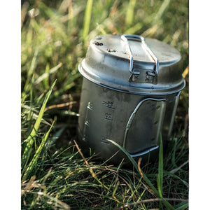 Snow Peak titanium camping pot with lid and folding handles sitting in grass