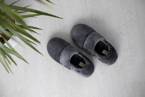 Pair of grey plush SnugToes slippers on a light wood floor