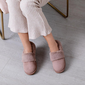 Person wearing mauve faux fur lined slippers with ribbed trousers