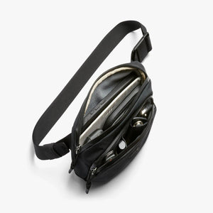 Open Bellroy sling bag with organized compartments containing a phone and keys