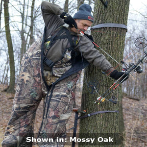 Hunter wearing Heater Body Suit in Mossy Oak camouflage pattern while using a compound bow in a tree stand