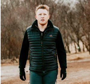 Man wearing a black Therm-ic quilted vest over a long sleeve shirt outdoors
