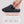 Hand inserting battery into grey heated slipper with battery life and temperature settings chart
