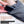 Hand inserting a black lithium polymer battery into a zippered pocket on a grey knit heated sock