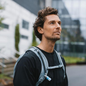 Man wearing a grey hydration backpack with a drinking tube