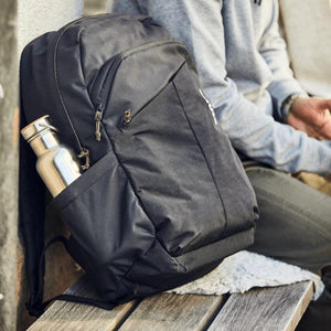 Black backpack with a metal water bottle in the side pocket resting on a wooden bench