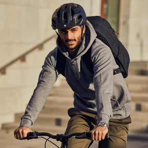 Man wearing a helmet and backpack riding a bicycle