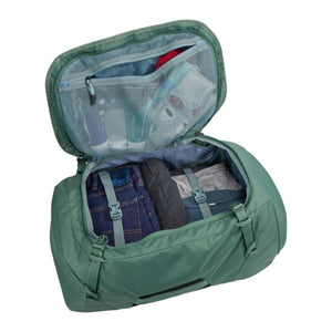 Open green Thule duffel bag packed with folded clothing and toiletries in mesh pockets