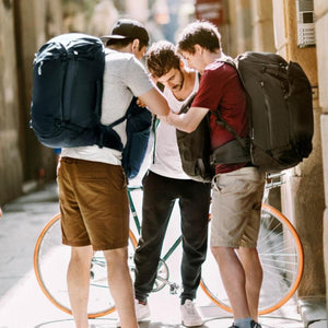 Three men standing in a city street wearing Thule travel backpacks