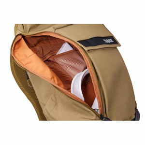 Open zippered compartment of a tan Thule backpack showing internal mesh pockets and storage