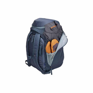 Thule blue backpack with side pocket open containing clothing and footwear